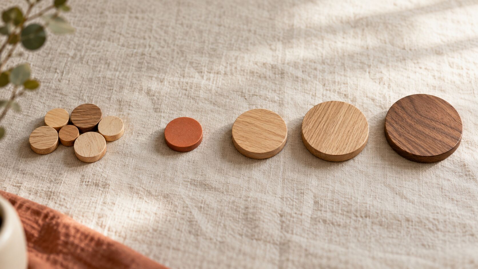 Overhead photo of wooden discs on linen: a crowded cluster of small discs on the left and larger, well spaced discs on the right